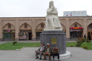 Drei Männer sitzen vor einer Statue